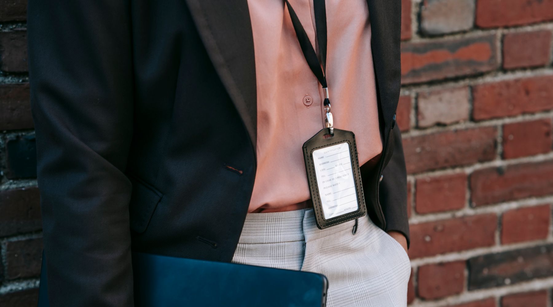 A person wearing a staff badge, carrying a laptop out of the office