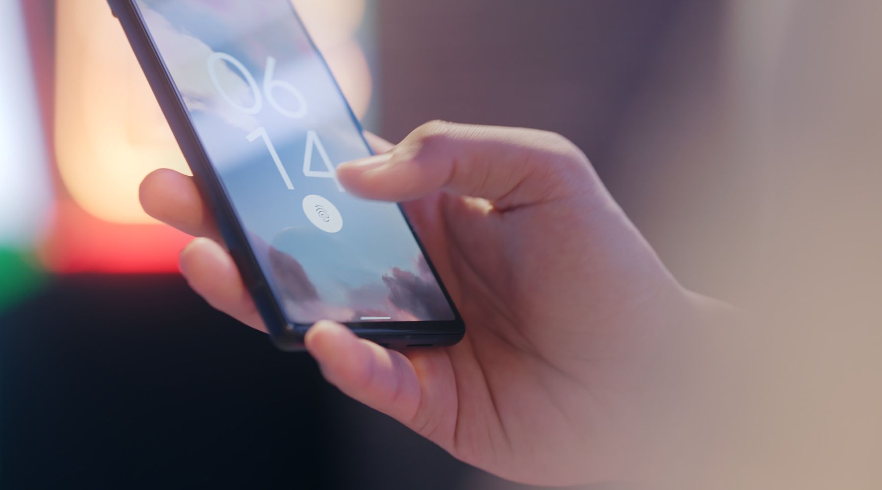 A hand holding a phone locked with a fingerprint sensor